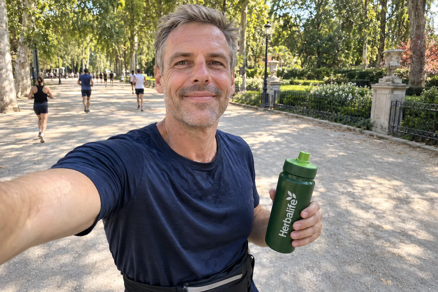 Smiling man with a water bottle on a run through the park